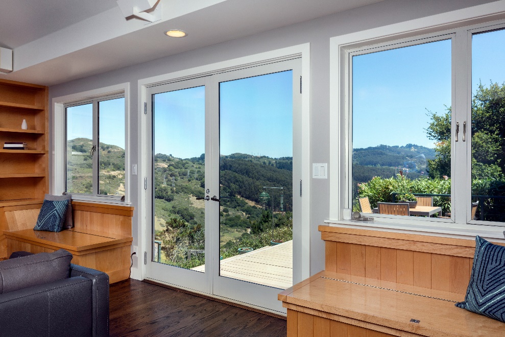 The interior of a home with white aluminum window frames surrounding both glass windows and doors.