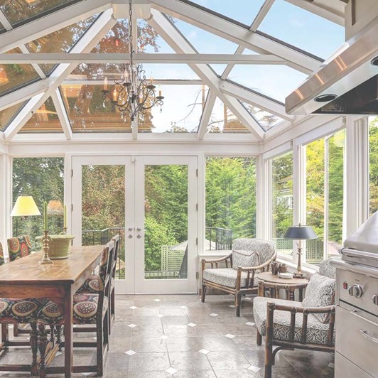 Straight eave sunroom with a dining table, comfortable chairs, and a grill.